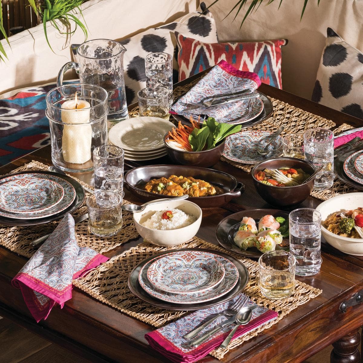 Table for four with colorful plates and sparkling glassware.