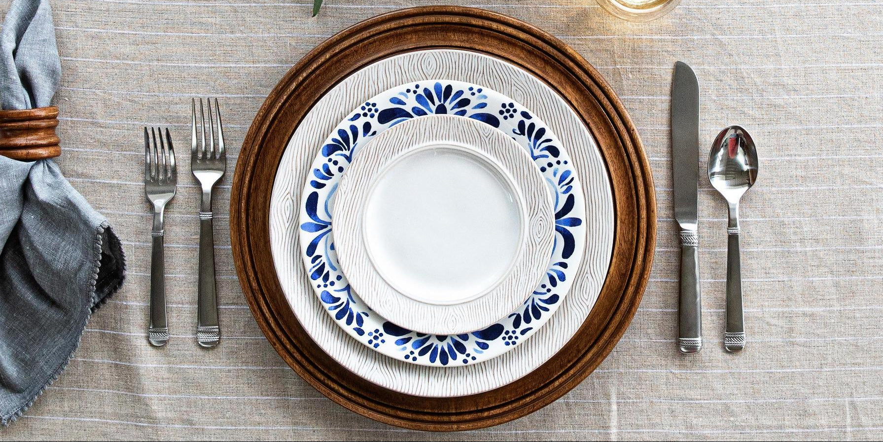 Dinnerware set with blue and white patterned plates on a textured tablecloth.