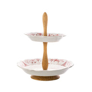 Two-tiered ceramic serving tray with wooden stand on a white background