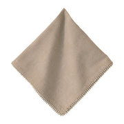 Beige napkin with pom-pom trim on a white background