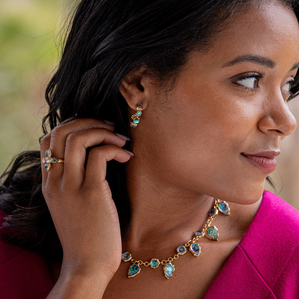 Woman wearing gold and turquoise jewelry, including earrings and a necklace.