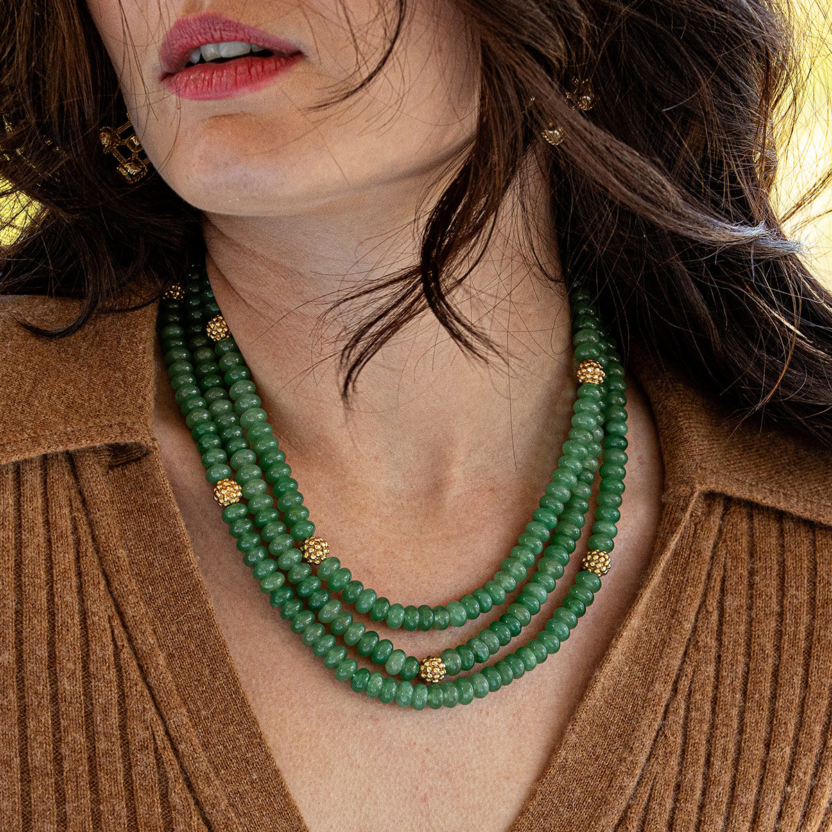 Close-up of a woman wearing a green beaded necklace with gold accents.