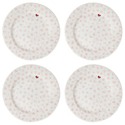 Four white plates with pink heart patterns on a white background
