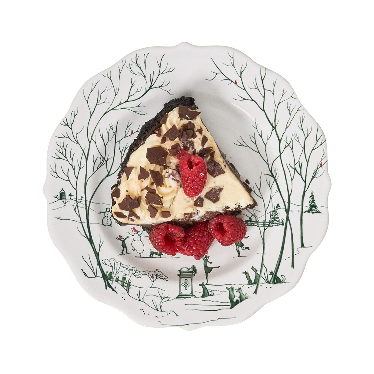 Slice of chocolate chip pie with raspberries on a decorative plate with winter scene design.