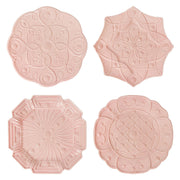 Set of four pink plates with embossed patterns on a white background