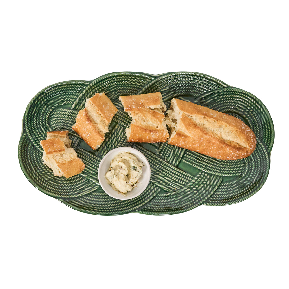 Green woven bread plate with sliced bread and a small bowl of spread on a white background