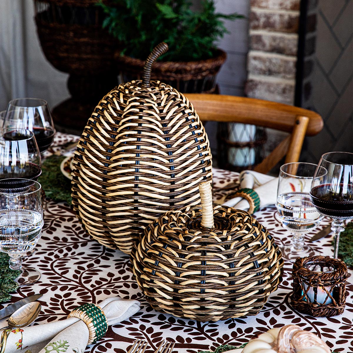 Wicker egg-shaped decorative items on a patterned tablecloth with glasses and cutlery.