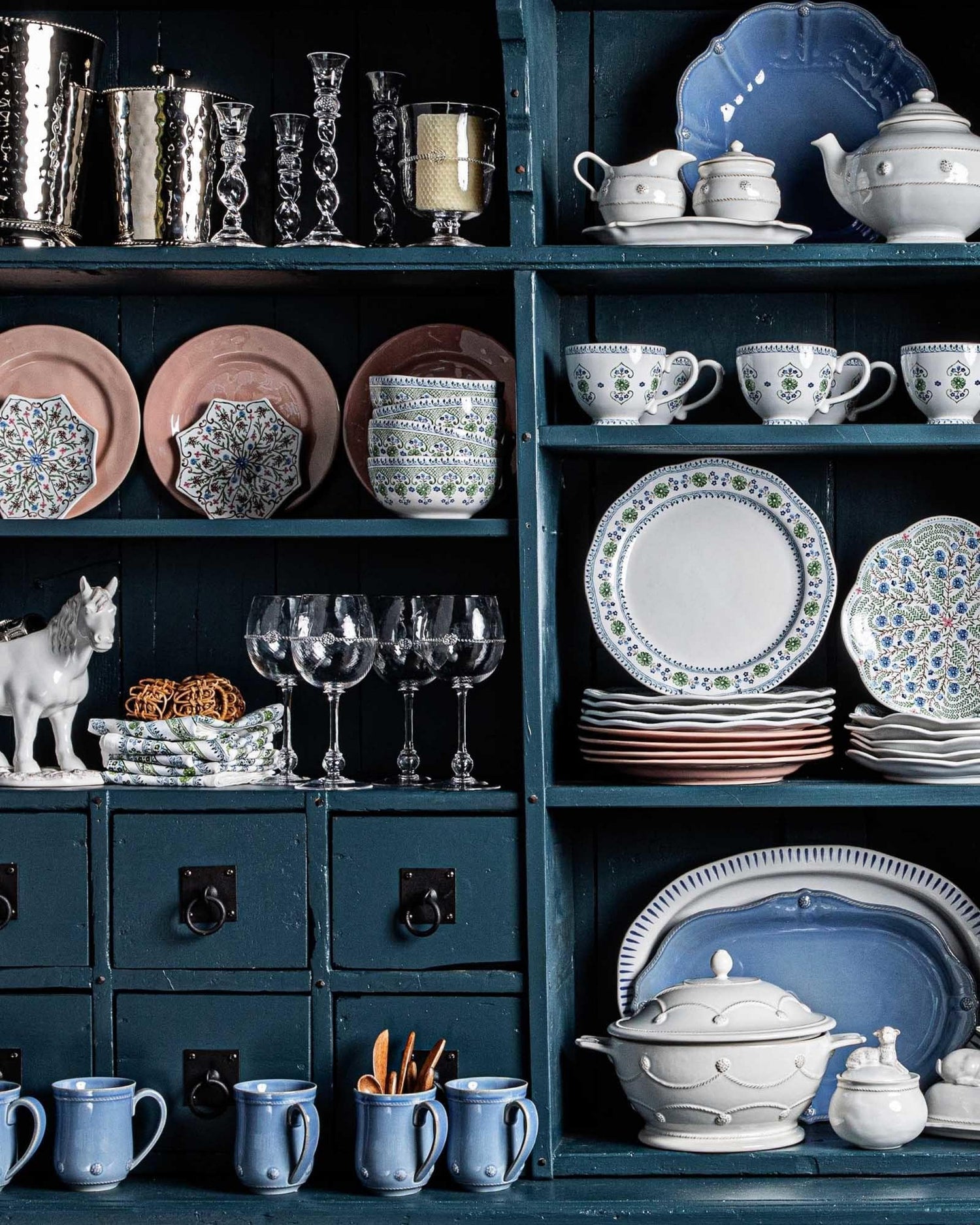 Collection of ceramic dishes and glasses on a dark blue shelf
