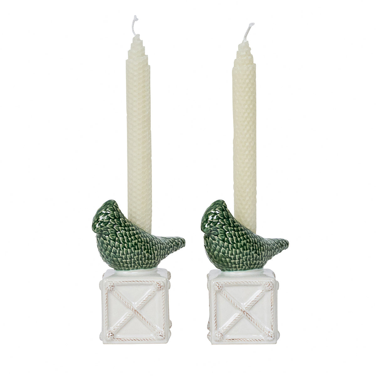 Two candle holders with green bird designs holding white candles on a white background