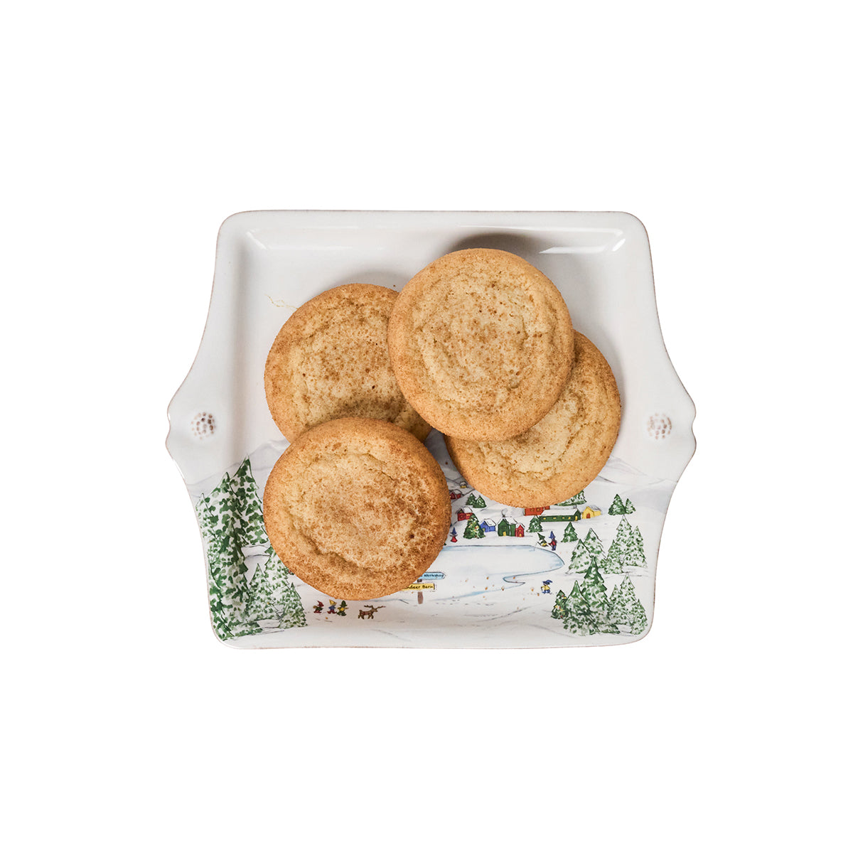 Three cookies on a decorative plate with a winter scene design.
