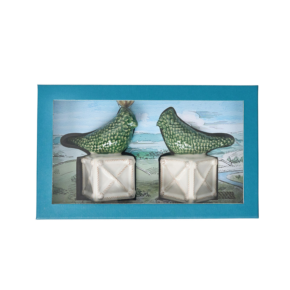 Two green bird figurines on white bases with a blue gift box