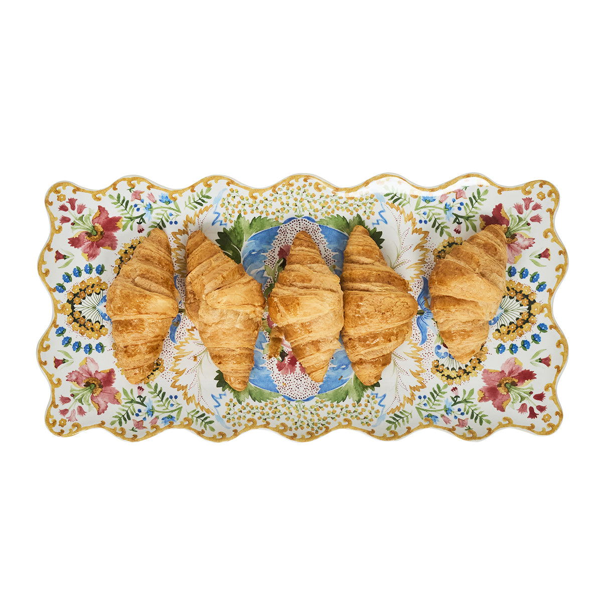 Five croissants on a decorative plate with floral patterns