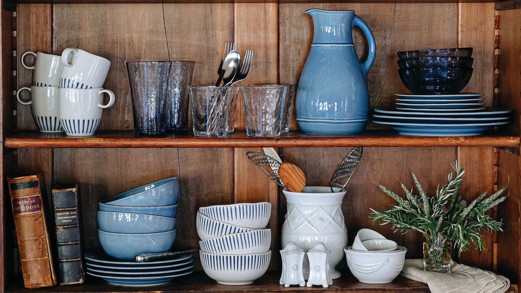 Wooden shelf with various ceramic and glass kitchenware on a wooden wall background