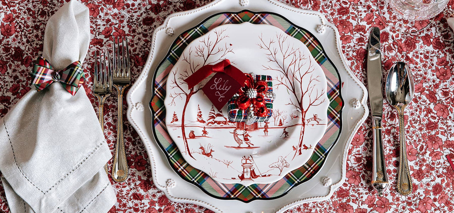 Christmas-themed place setting with reindeer design on a red patterned tablecloth.