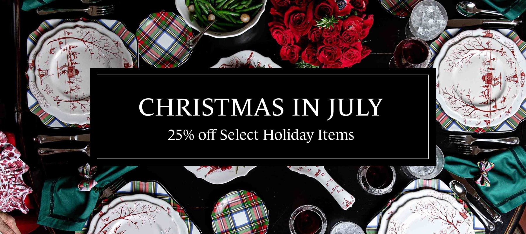A promotional banner for a holiday sale featuring a styled Christmas table setting with white plates, red patterns, green napkins, red roses, and a central black text box that reads 'CHRISTMAS IN JULY 25% off Select Holiday Items'.