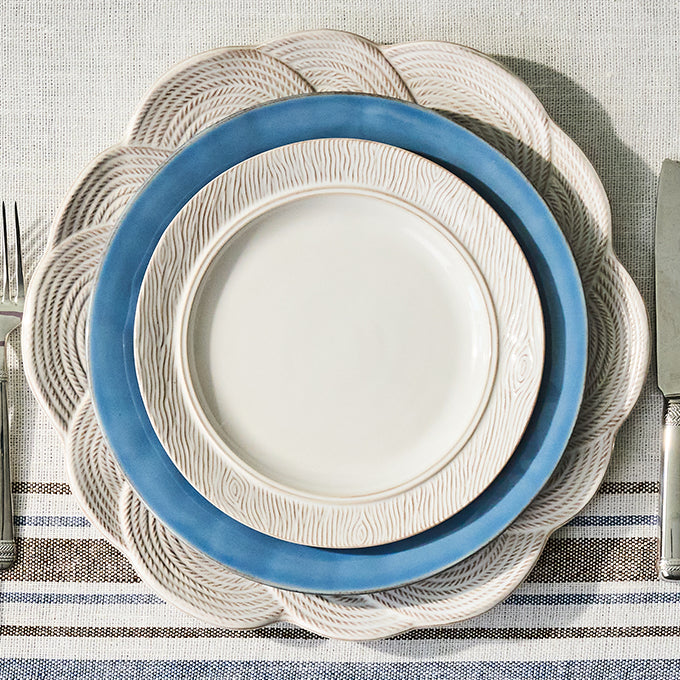 Set of stacked plates with a blue rim on a striped tablecloth