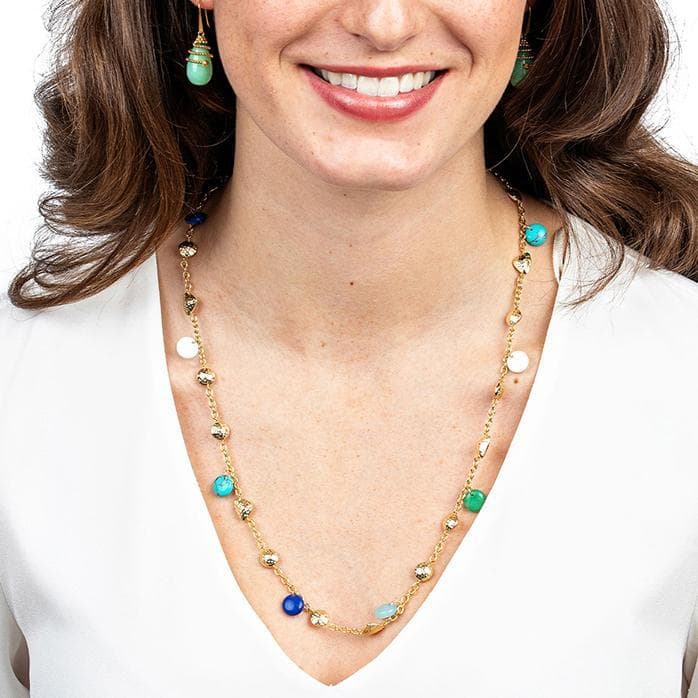 Woman wearing a gold necklace with turquoise and blue beads on a white background