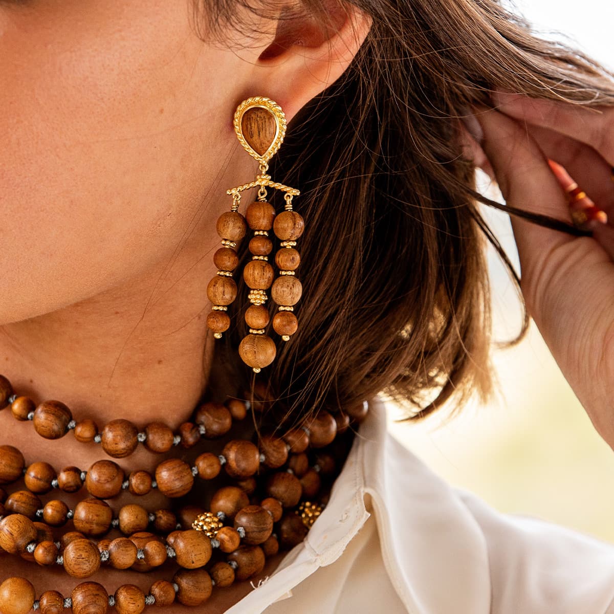 Close-up of a person wearing wooden beaded necklaces and earrings.