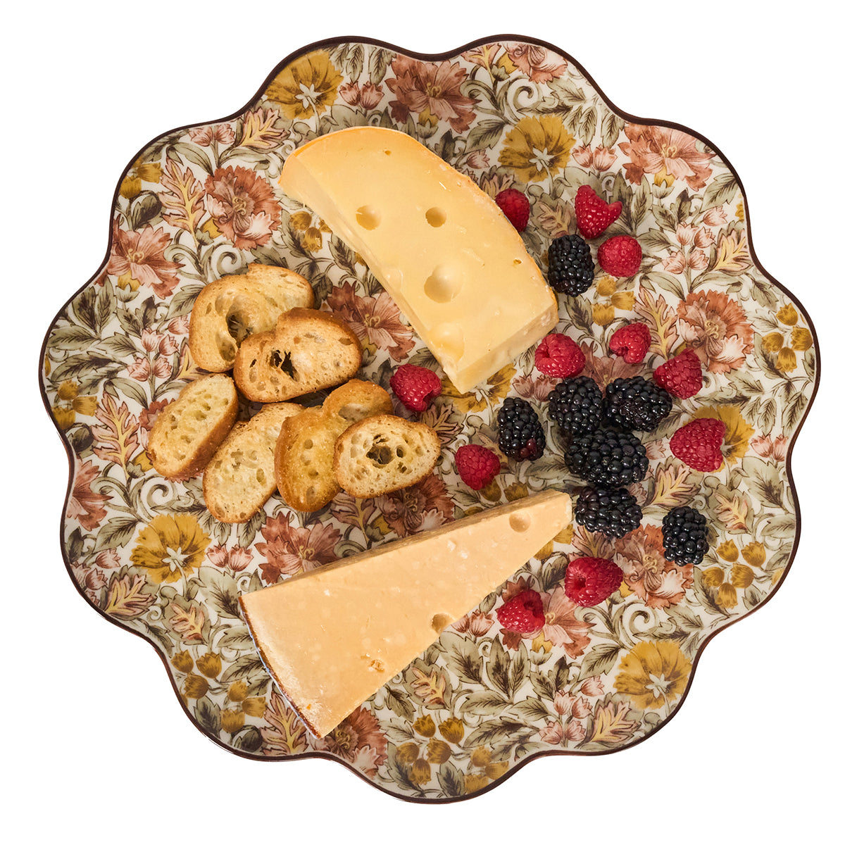 Decorative plate with cheese, crackers, and berries on a floral patterned background