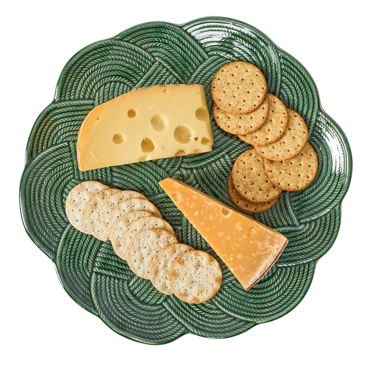 Green decorative plate with two types of cheese and crackers on a white background