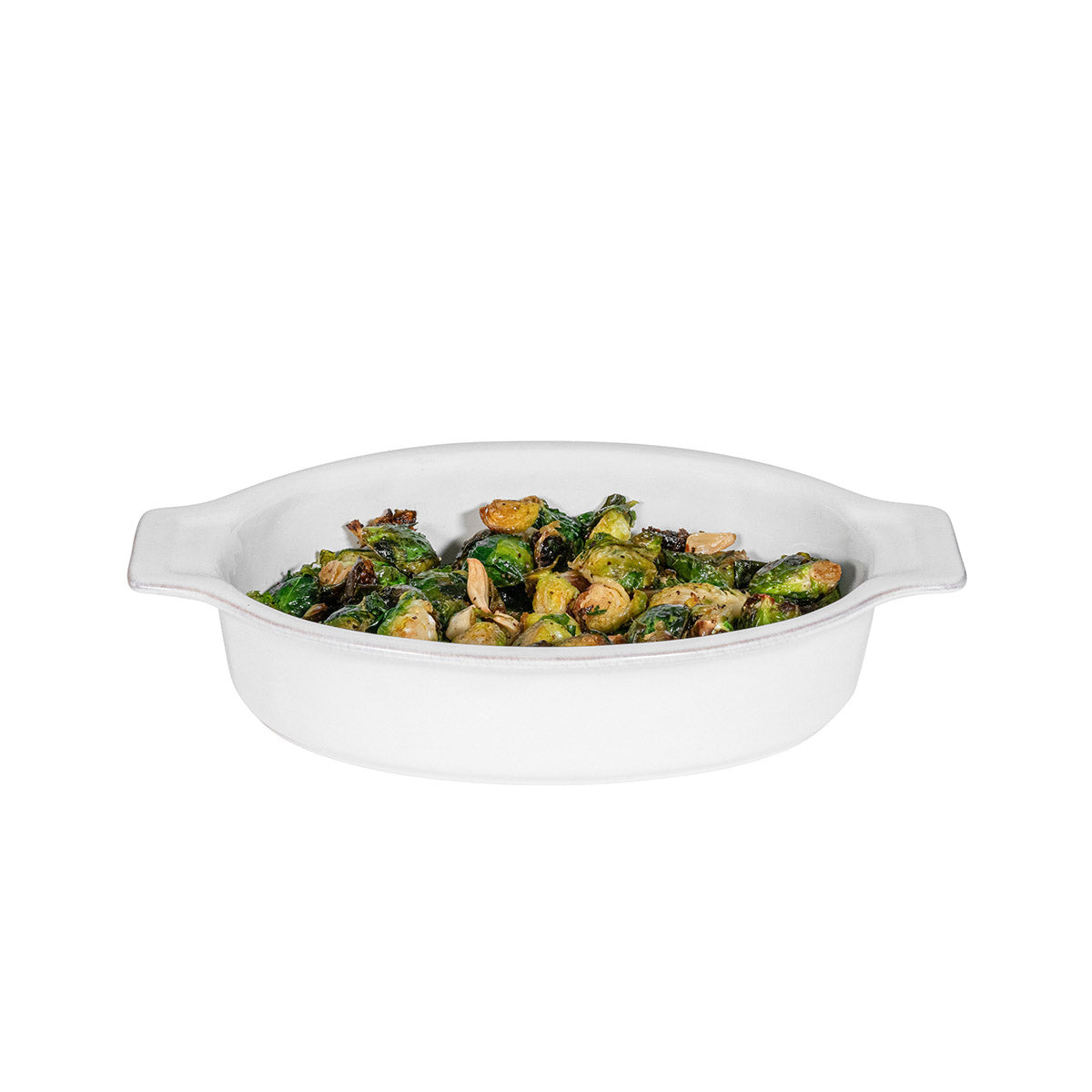 White oval dish with roasted vegetables on a white background